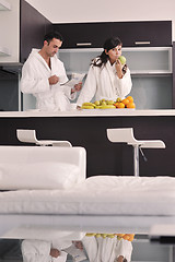 Image showing Happy couple reading the newspaper in the kitchen at breakfast