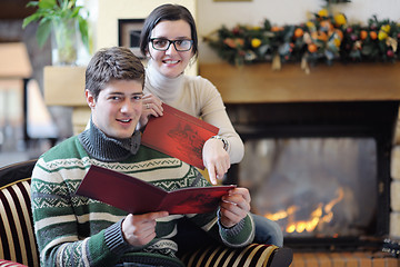 Image showing Young romantic couple sitting and relaxing in front of fireplace