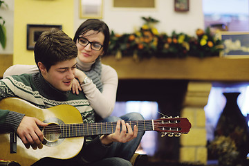 Image showing Young romantic couple sitting and relaxing in front of fireplace