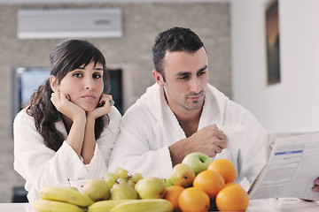 Image showing Happy couple reading the newspaper in the kitchen at breakfast