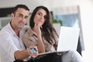 Image showing joyful couple relax and work on laptop computer at modern home