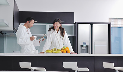 Image showing Happy couple reading the newspaper in the kitchen at breakfast