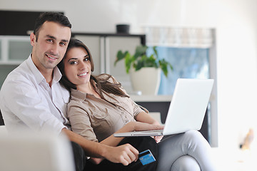 Image showing joyful couple relax and work on laptop computer at modern home