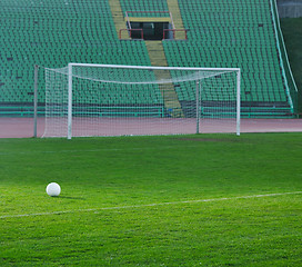 Image showing Soccer ball on grass at goal and stadium in background