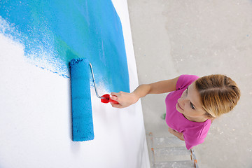 Image showing happy smiling woman painting interior of house