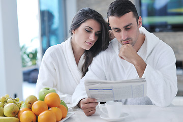 Image showing Happy couple reading the newspaper in the kitchen at breakfast