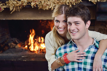 Image showing Young romantic couple sitting and relaxing in front of fireplace