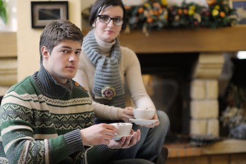 Image showing Young romantic couple sitting on sofa in front of fireplace at h