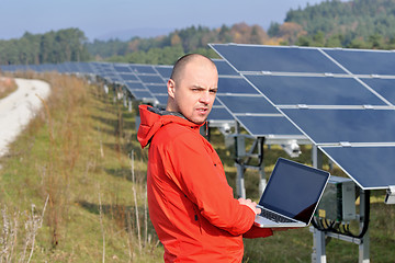 Image showing engineer using laptop at solar panels plant field