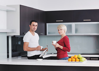 Image showing Happy couple reading the newspaper in the kitchen at breakfast