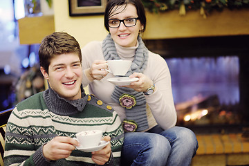 Image showing Young romantic couple sitting and relaxing in front of fireplace