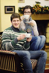 Image showing Young romantic couple sitting on sofa in front of fireplace at h