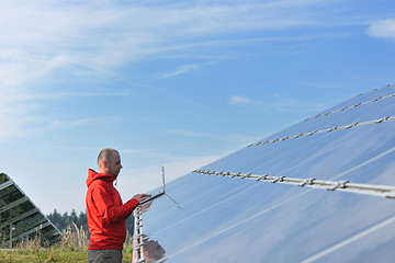 Image showing engineer using laptop at solar panels plant field