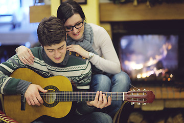 Image showing Young romantic couple sitting and relaxing in front of fireplace