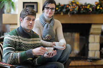 Image showing Young romantic couple sitting and relaxing in front of fireplace