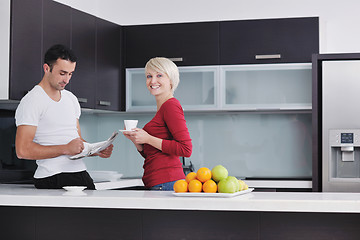 Image showing Happy couple reading the newspaper in the kitchen at breakfast