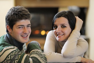 Image showing Young romantic couple sitting on sofa in front of fireplace at h