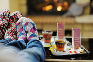 Image showing Young romantic couple sitting and relaxing in front of fireplace