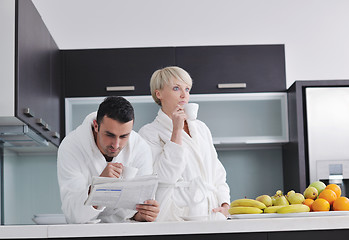 Image showing Happy couple reading the newspaper in the kitchen at breakfast