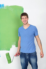 Image showing handsome young man paint white wall in color