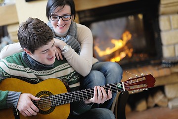 Image showing Young romantic couple sitting on sofa in front of fireplace at h