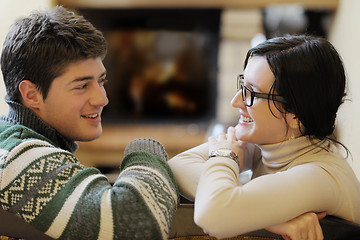 Image showing Young romantic couple sitting and relaxing in front of fireplace