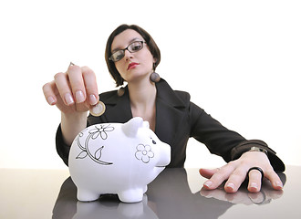 Image showing business woman putting money coins in piggy bank