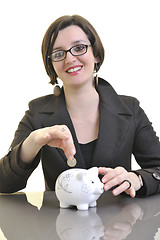 Image showing business woman putting money coins in piggy bank