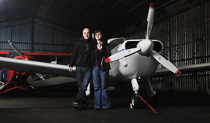 Image showing happy young couple posing in front of private airplane
