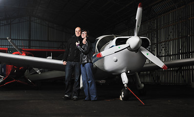 Image showing happy young couple posing in front of private airplane
