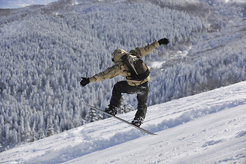 Image showing freestyle snowboarder jump and ride