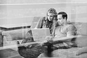 Image showing happy couple have fun and work on laptop at home on red sofa