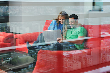 Image showing happy couple have fun and work on laptop at home on red sofa