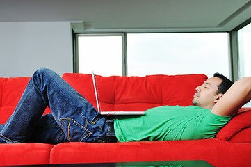 Image showing man relaxing on sofa and work on laptop computer