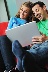 Image showing happy couple have fun and work on laptop at home on red sofa