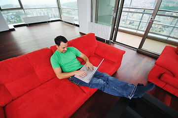 Image showing man relaxing on sofa and work on laptop computer