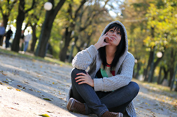 Image showing Cute young woman sitting outdoors in nature