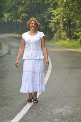 Image showing middle age woman walk on white line on road outdoor