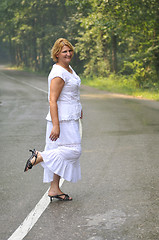 Image showing middle age woman walk on white line on road outdoor