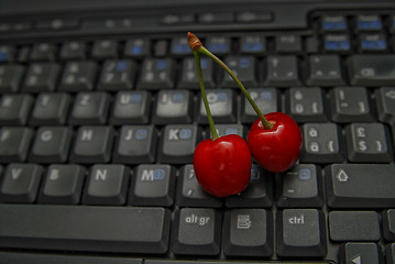 Image showing fresh cherry on laptop keyboard 