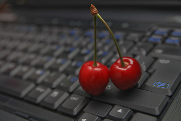 Image showing fresh cherry on laptop keyboard 