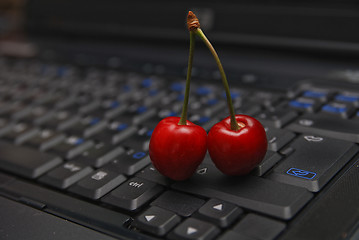 Image showing fresh cherry on laptop keyboard 