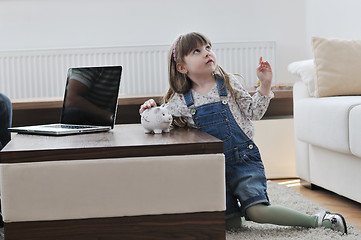 Image showing cute little girl painting piggy bank