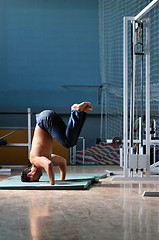 Image showing Young man performing  handstand in fitness studio