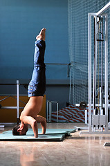 Image showing Young man performing  handstand in fitness studio