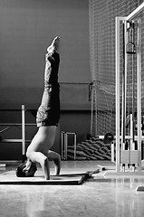 Image showing Young man performing  handstand in fitness studio