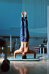 Image showing Young man performing  handstand in fitness studio