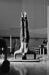 Image showing Young man performing  handstand in fitness studio