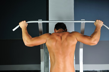 Image showing young man with strong arms working out in gym