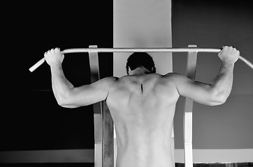 Image showing young man with strong arms working out in gym